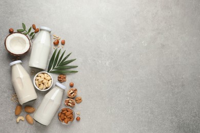 Photo of Vegan milk and different nuts on grey table, flat lay. Space for text