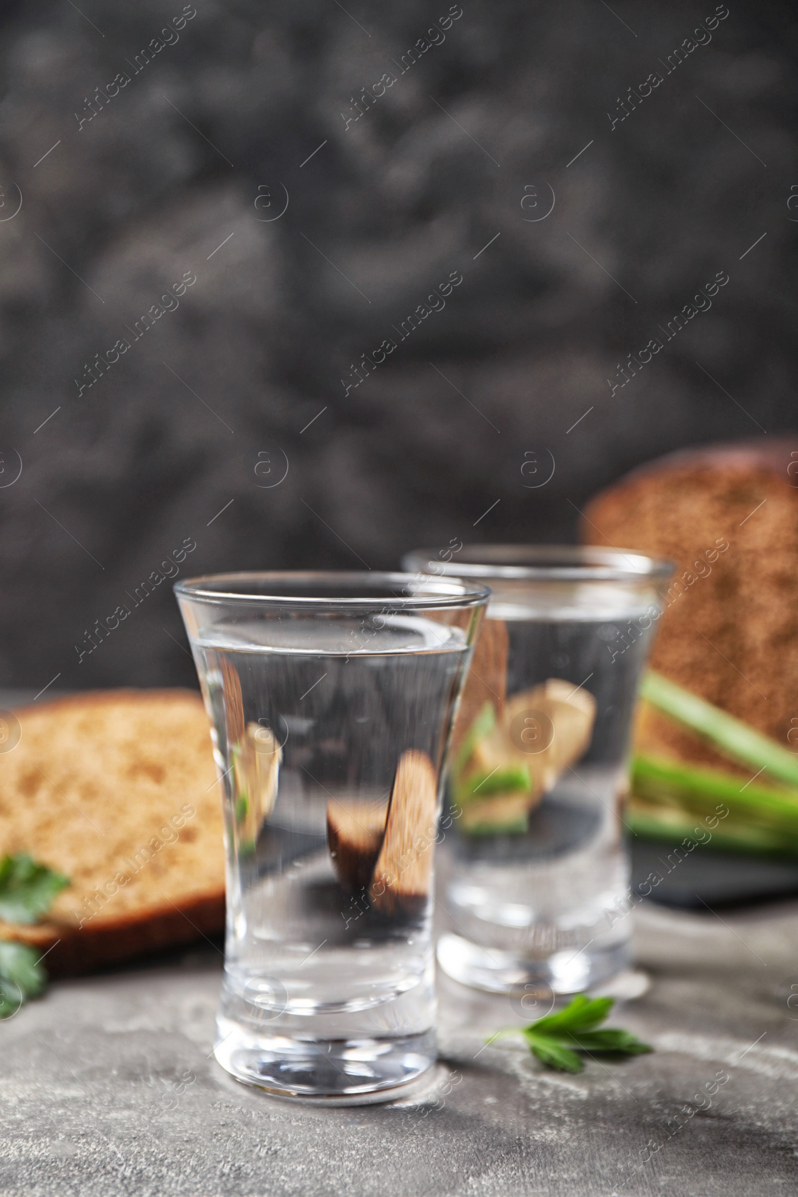 Photo of Cold Russian vodka with snacks on grey table, closeup