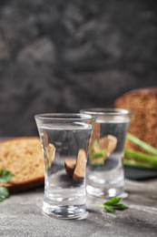 Photo of Cold Russian vodka with snacks on grey table, closeup