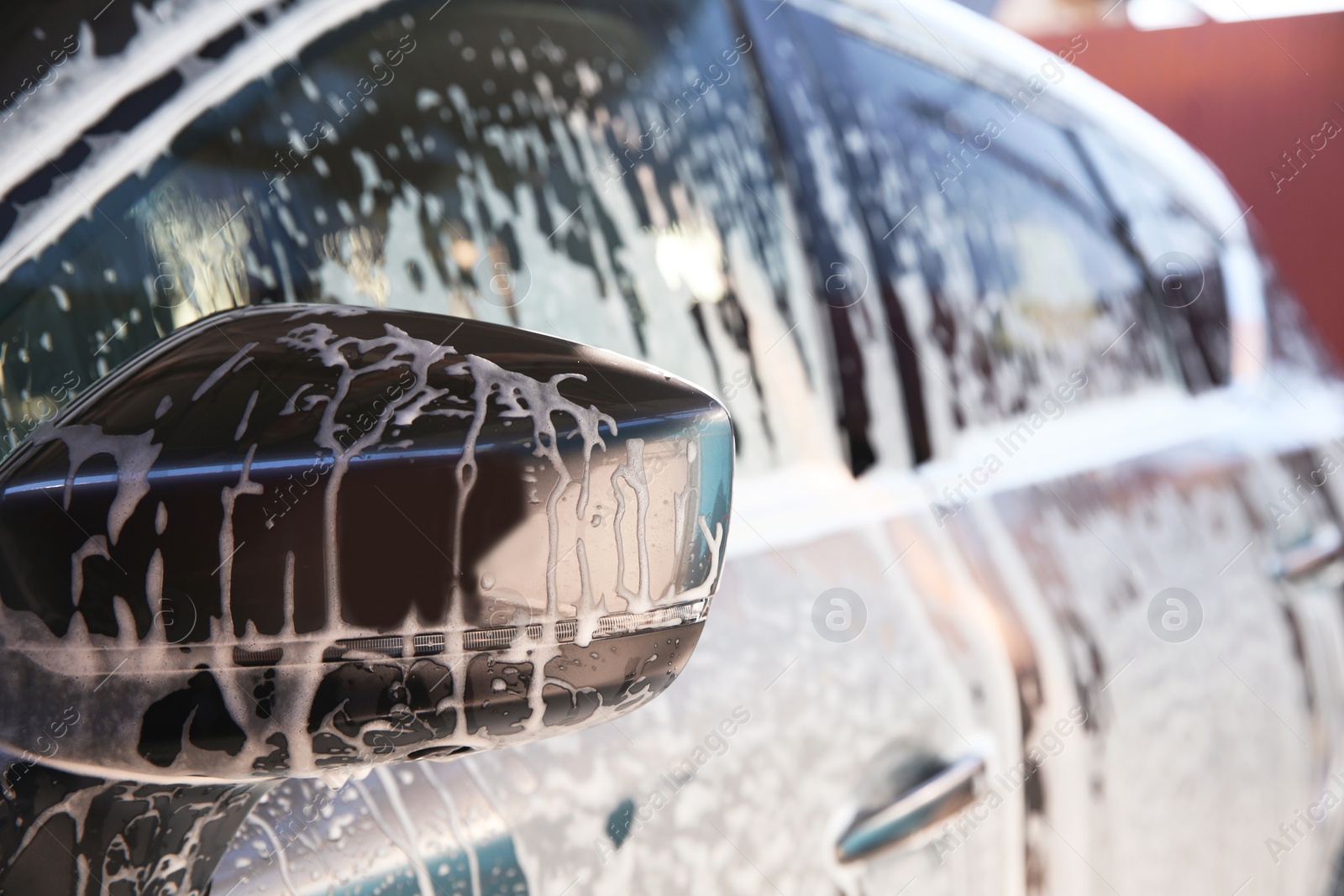 Photo of Automobile covered with foam at car wash, closeup