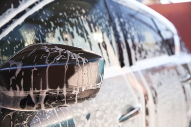 Automobile covered with foam at car wash, closeup