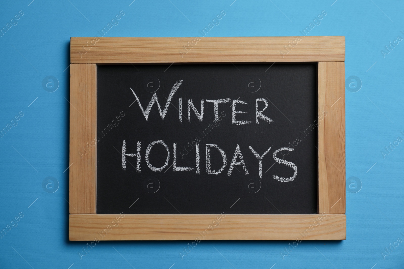 Photo of Chalkboard with words Winter Holidays on light blue background, top view