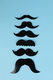 Photo of Fake paper mustaches on light blue background, flat lay