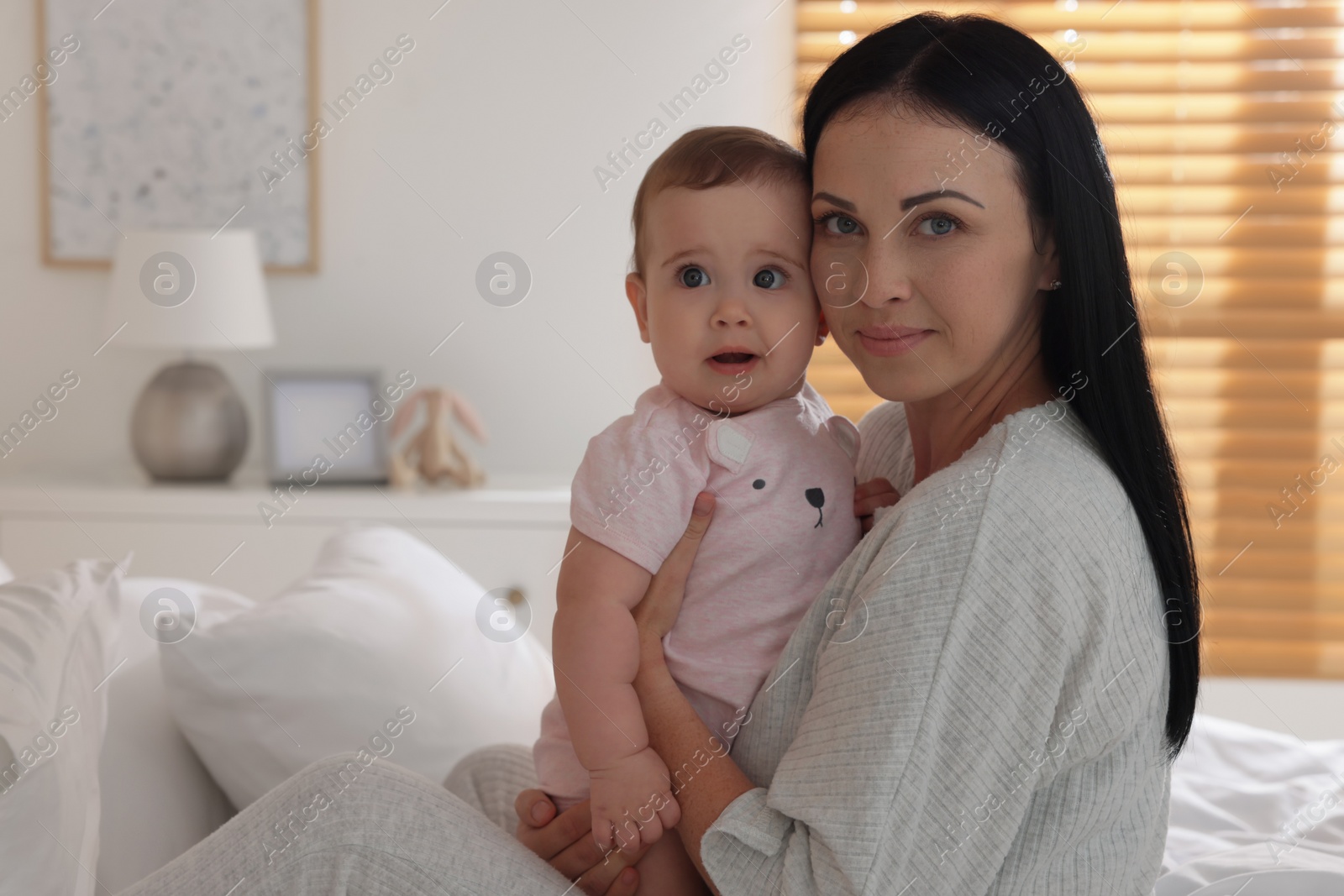 Photo of Happy woman with her little baby on bed at home