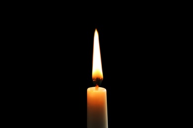 Photo of Wax candle burning on black background