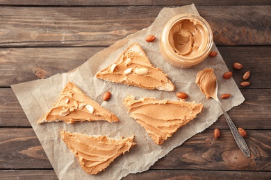 Photo of Tasty toasts with peanut butter and jar on table