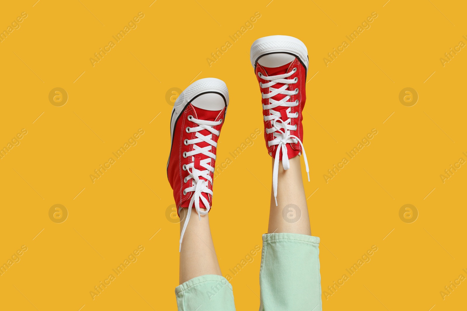 Photo of Woman in stylish gumshoes on yellow background, closeup