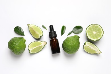 Photo of Glass bottle of bergamot essential oil and fresh fruits on white background, flat lay