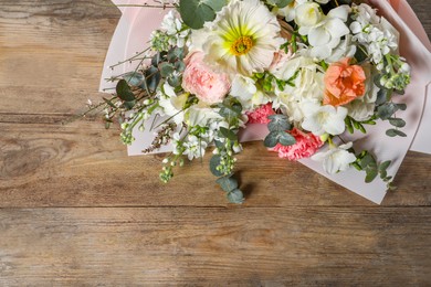 Photo of Bouquet of beautiful flowers on wooden table, above view. Space for text