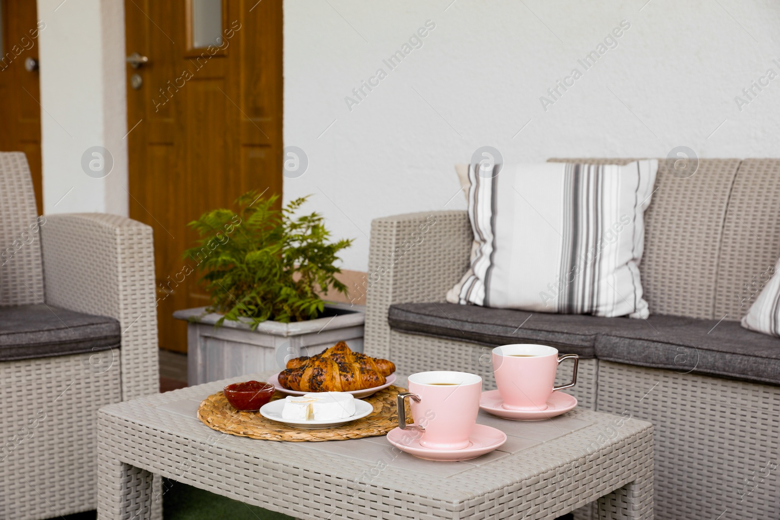 Outdoor breakfast with tea and croissants on rattan table on terrace Photo of Outdoor breakfast with tea and croissants on rattan table on terrace