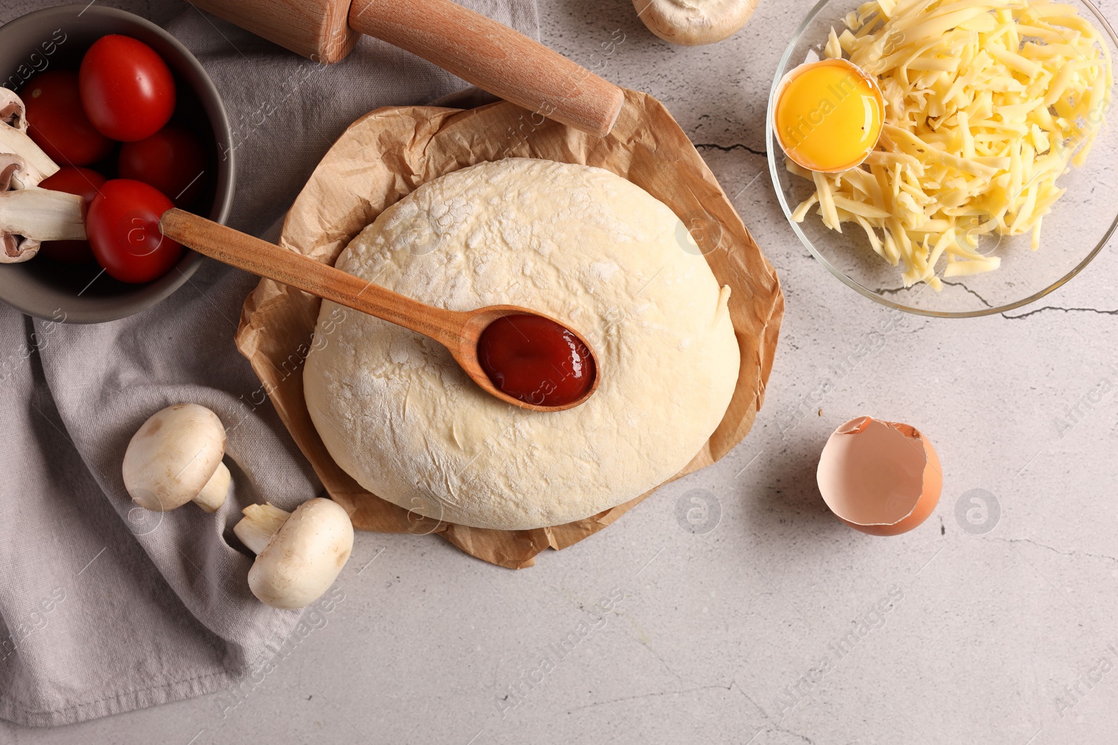 Photo of Pizza dough, products and rolling pin on gray textured table, flat lay