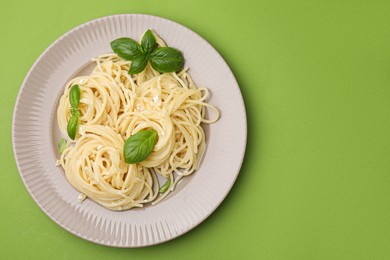 Photo of Delicious pasta with brie cheese and basil leaves on light green background, top view. Space for text