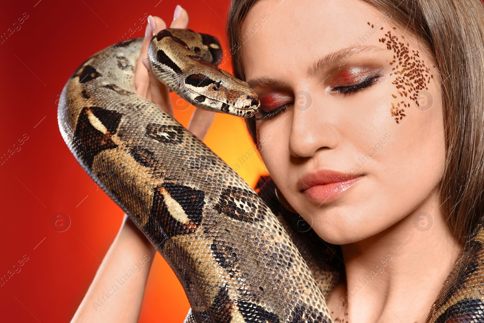 Photo of Beautiful woman with boa constrictor on bright colorful background, closeup