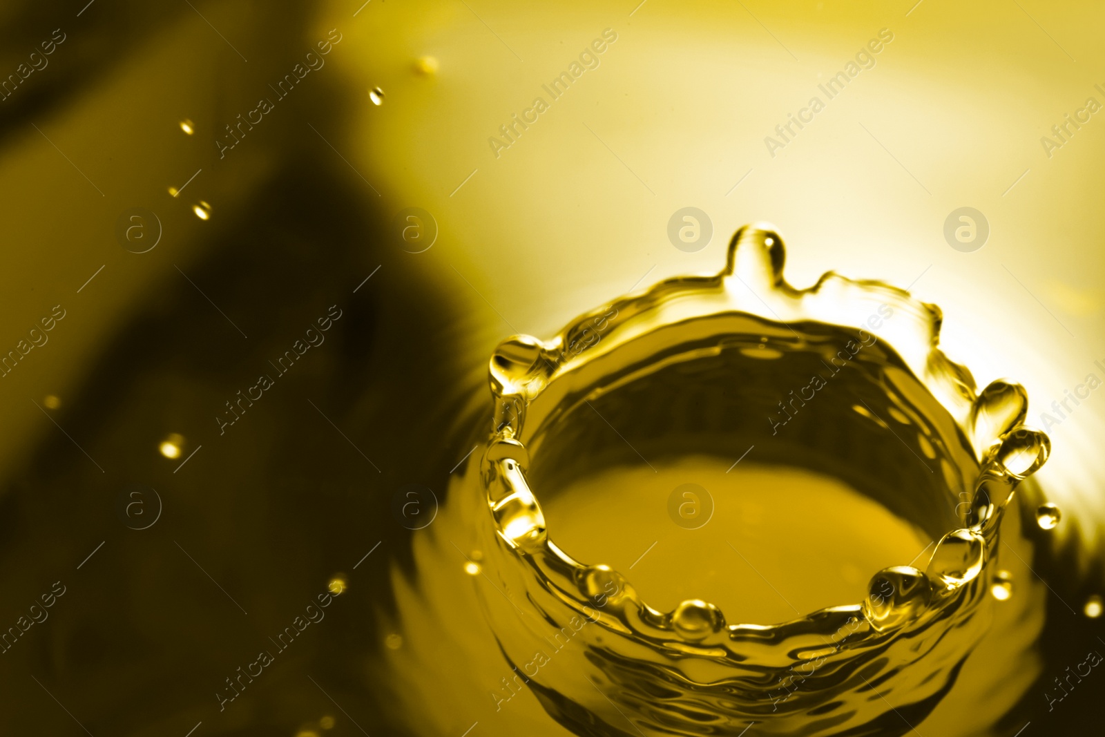 Image of Splash of golden oily liquid with drops as background, closeup