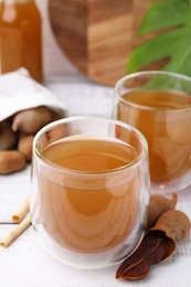 Photo of Tamarind juice and fresh fruits on white table, closeup