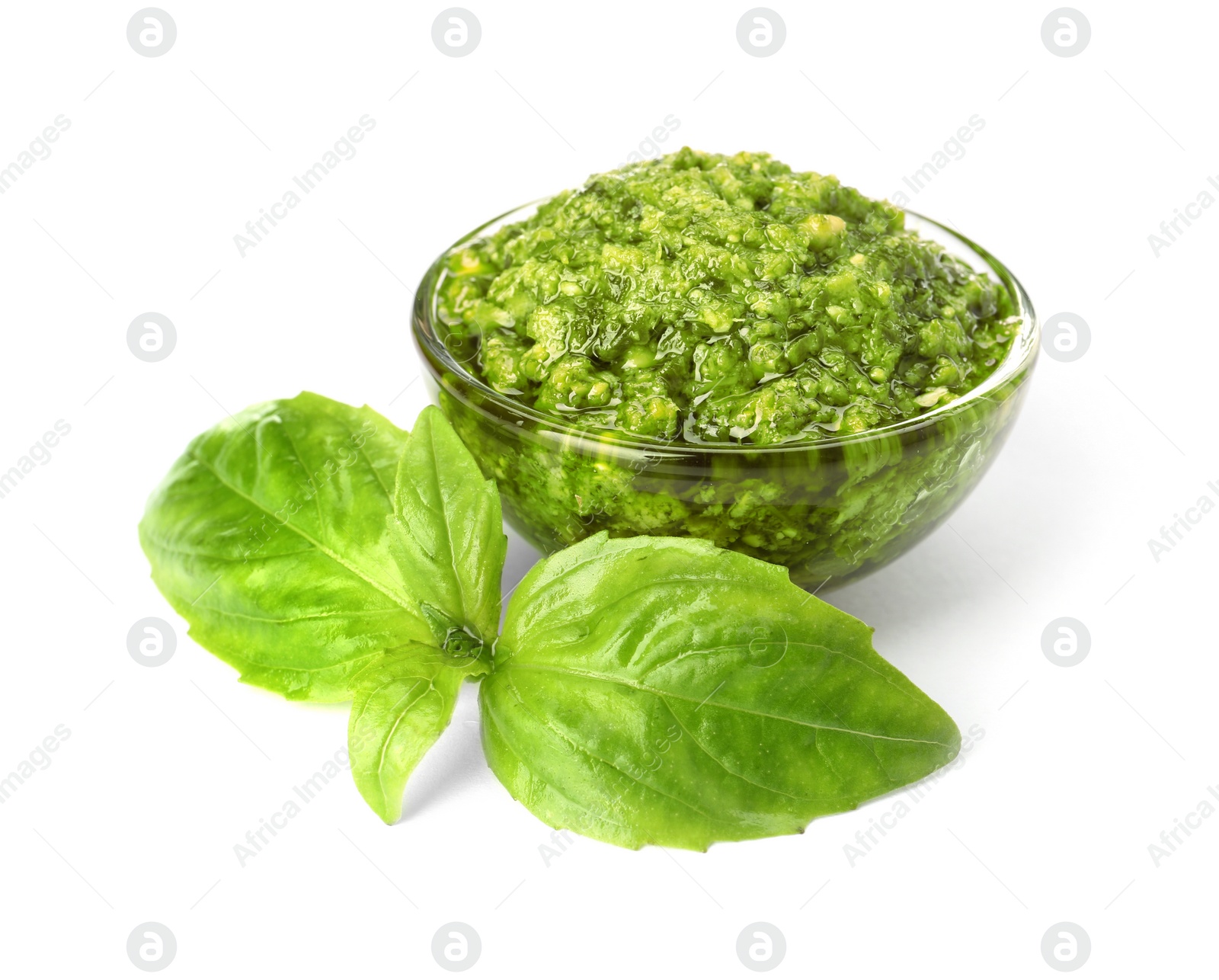 Photo of Bowl of tasty pesto sauce with basil leaves isolated on white