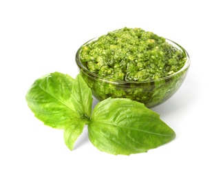 Photo of Bowl of tasty pesto sauce with basil leaves isolated on white