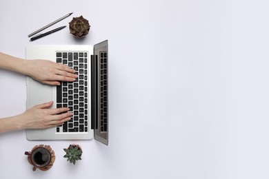 Photo of Woman using laptop at white table, top view. Space for text