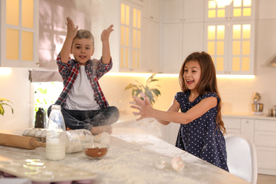 Photo of Cute little children having fun in kitchen. Cooking dough