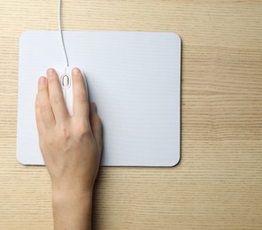 Photo of Woman using wired computer mouse on wooden table, top view. Space for text