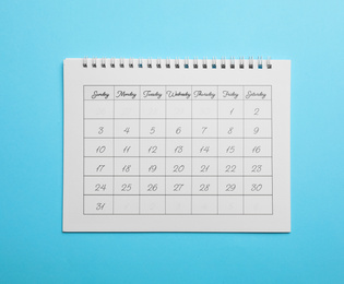 Paper calendar on light blue background, top view