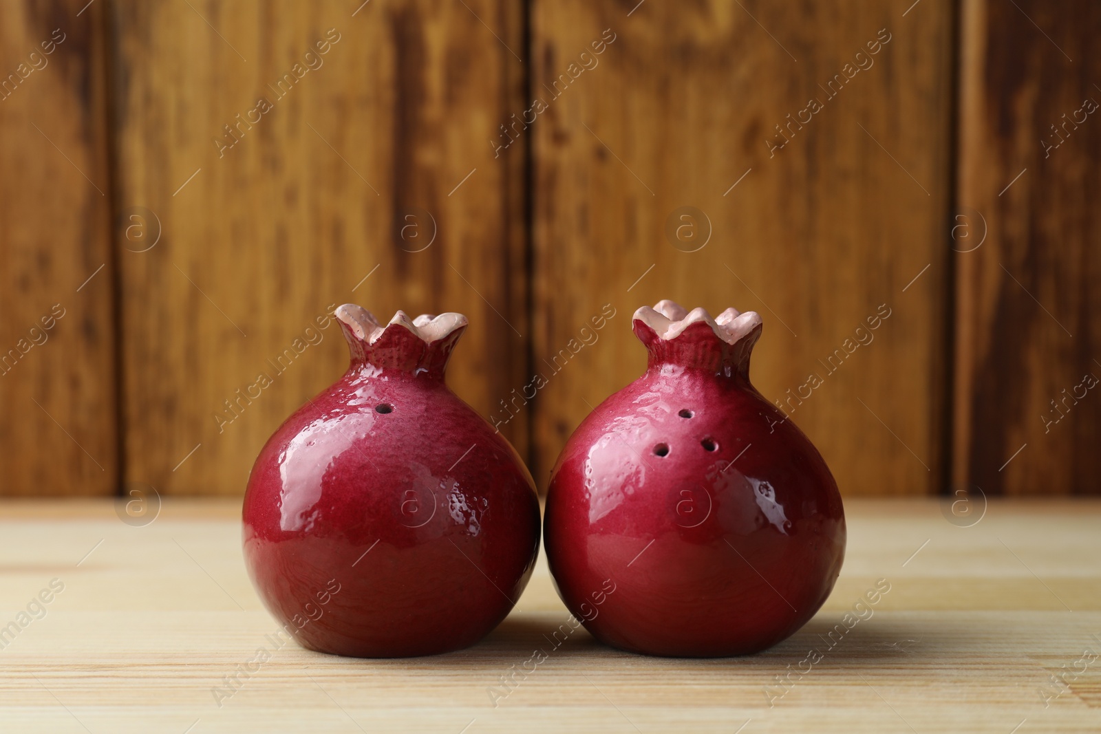 Photo of Pomegranate shaped salt and pepper shakers on light wooden table