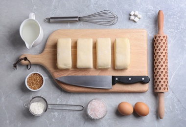 Flat lay composition with puff pastry dough and ingredients on grey table