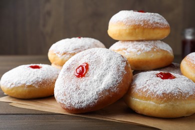 Many delicious donuts with jelly and powdered sugar on wooden table, closeup