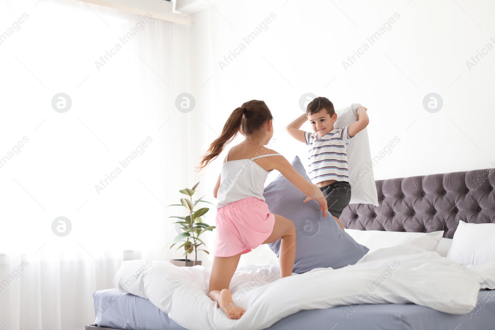 Photo of Happy children having pillow fight in bedroom