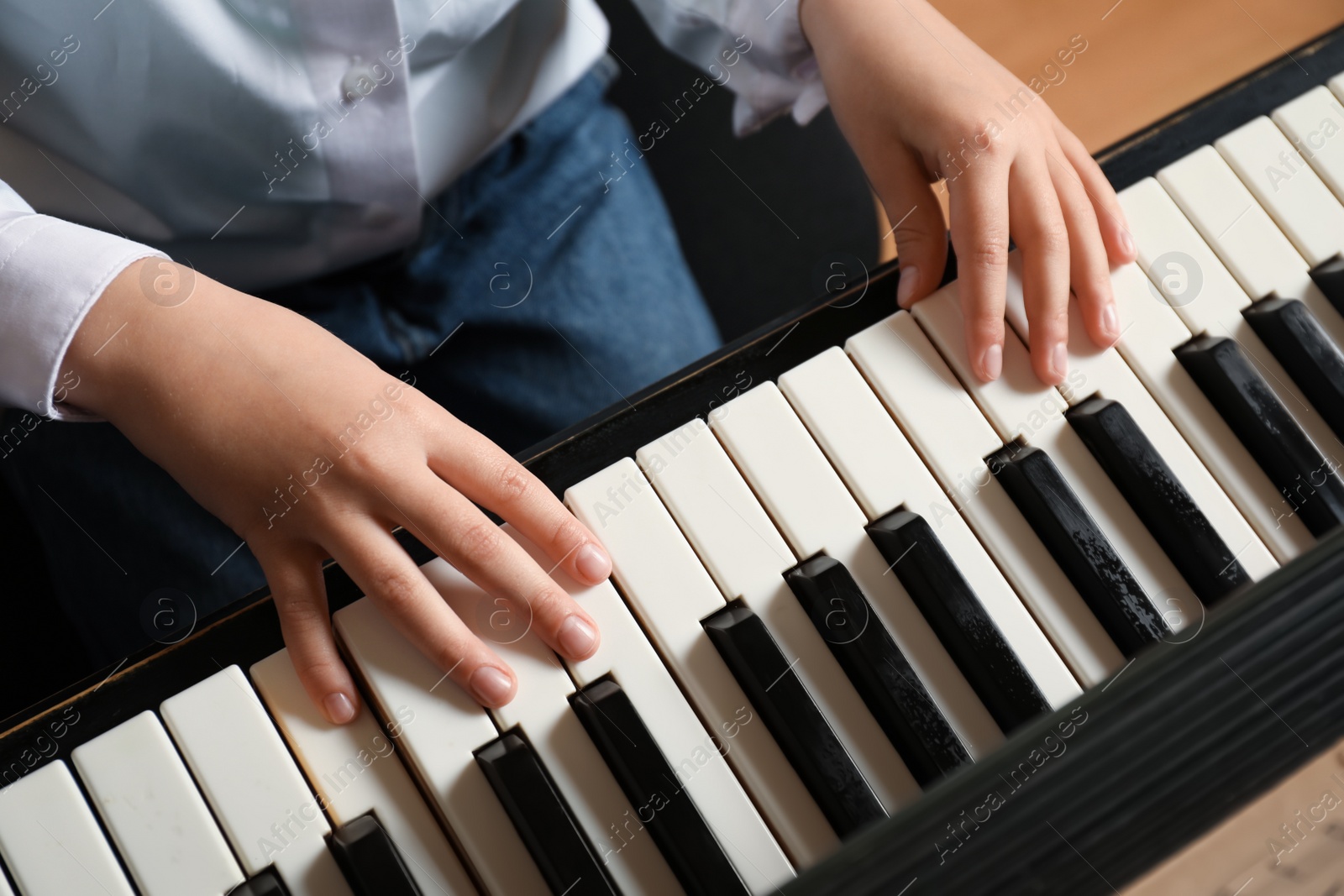 Photo of Little child playing piano, above view. Music lesson