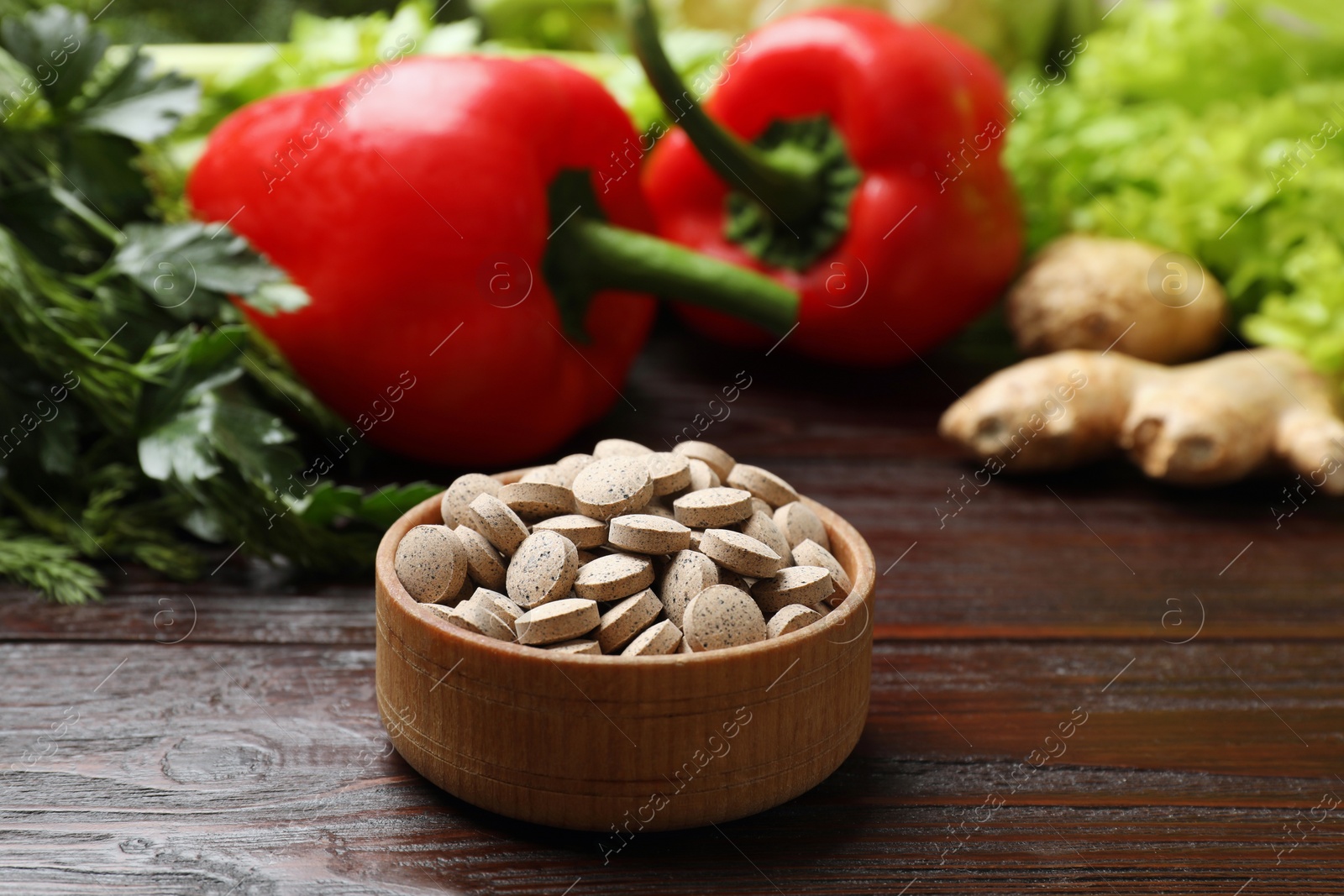 Photo of Dietary supplements. Pills in bowl and food products on wooden table