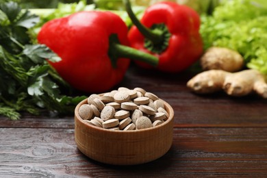 Dietary supplements. Pills in bowl and food products on wooden table