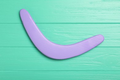 Boomerang on turquoise wooden background, top view