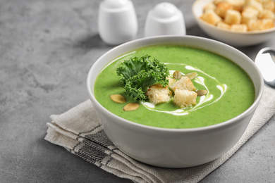 Photo of Tasty kale soup with croutons on grey table