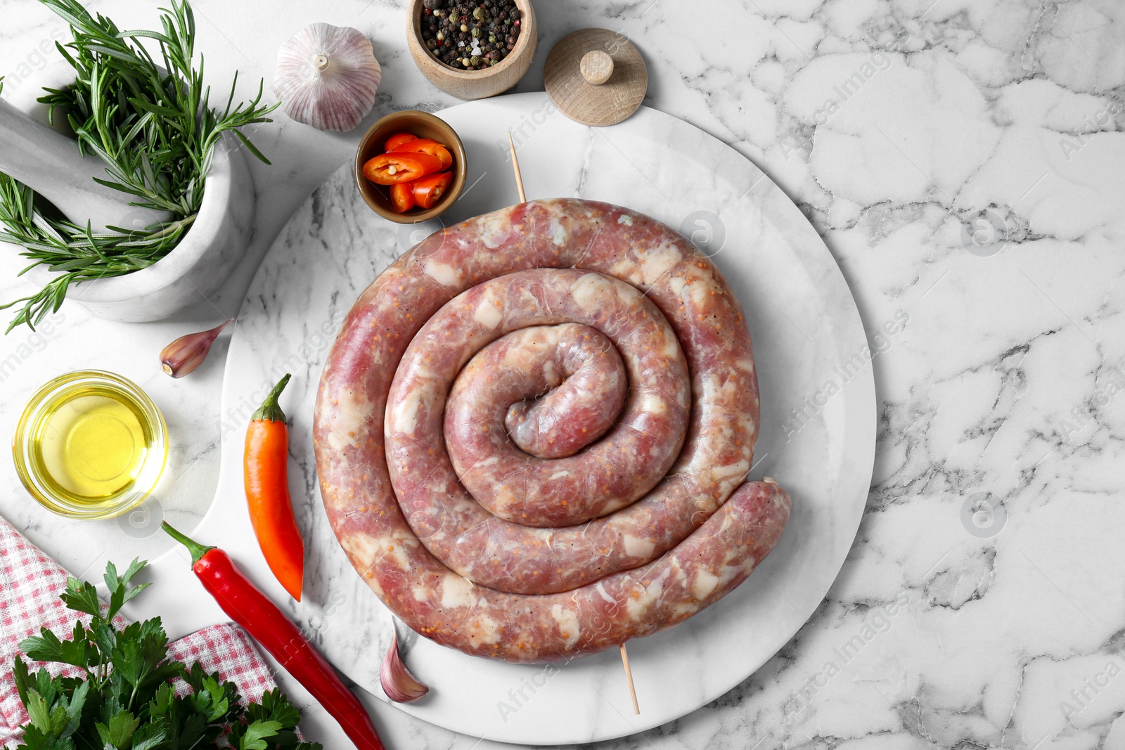 Photo of Raw homemade sausage, spices and other products on white marble table, flat lay