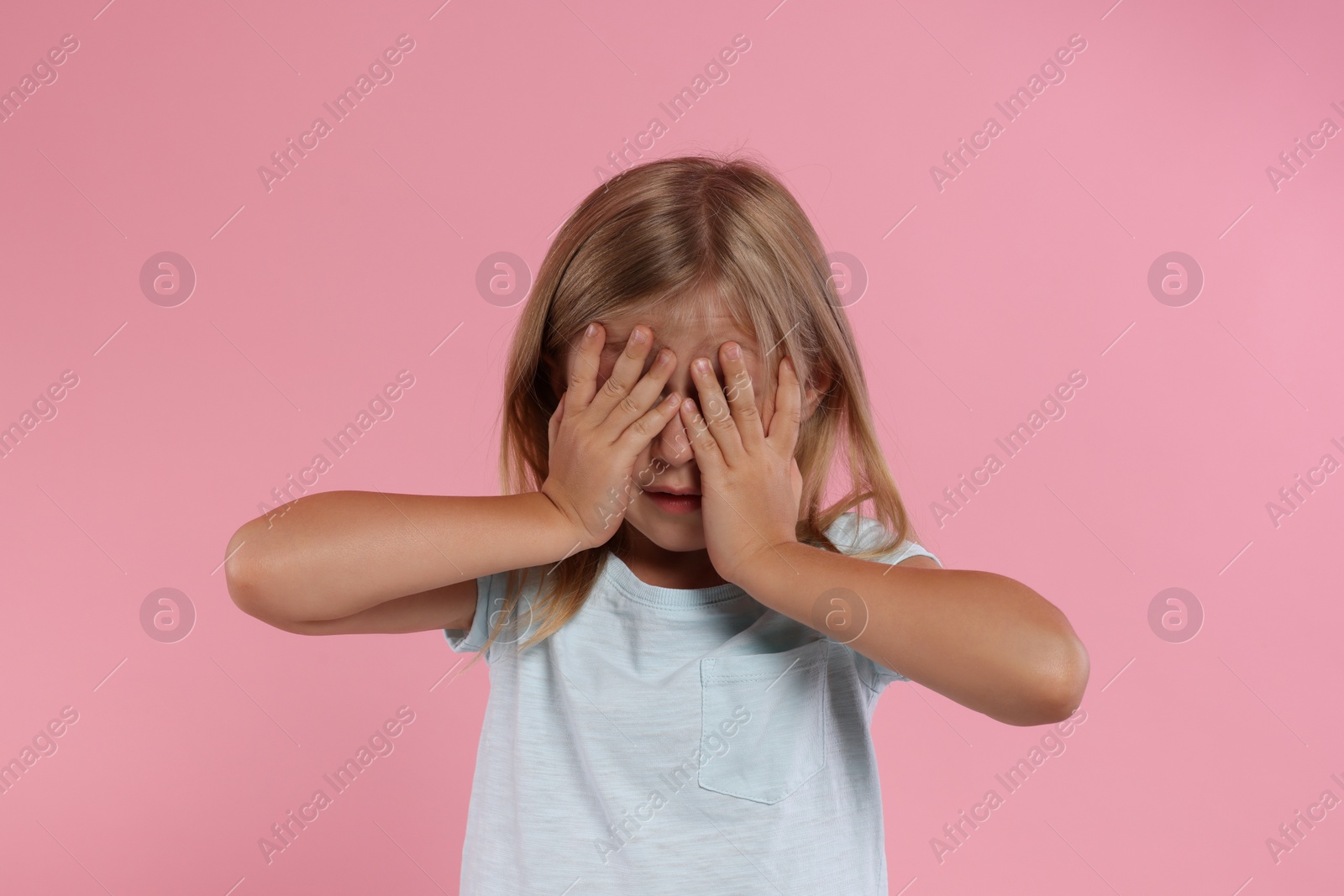 Photo of Resentful girl covering face with hands on pink background