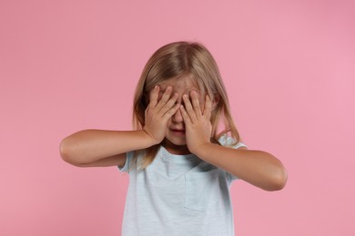 Resentful girl covering face with hands on pink background