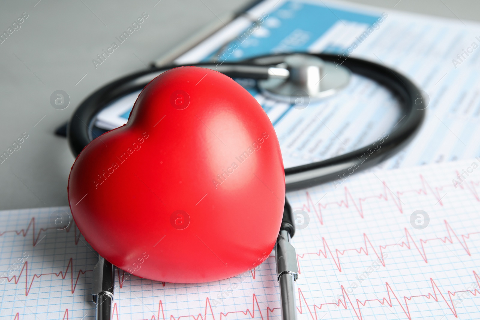 Photo of Composition with red heart and stethoscope on gray table. Cardiology concept