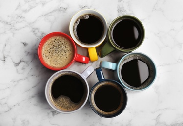 Photo of Many cups with tasty aromatic coffee on marble table, flat lay
