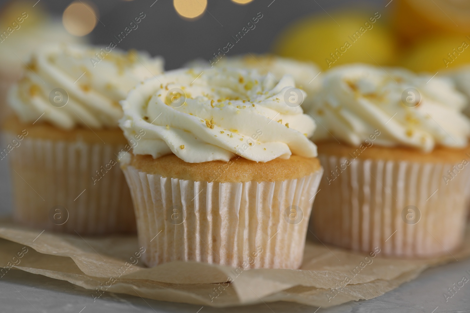 Photo of Delicious cupcakes with white cream and lemon zest on table, closeup