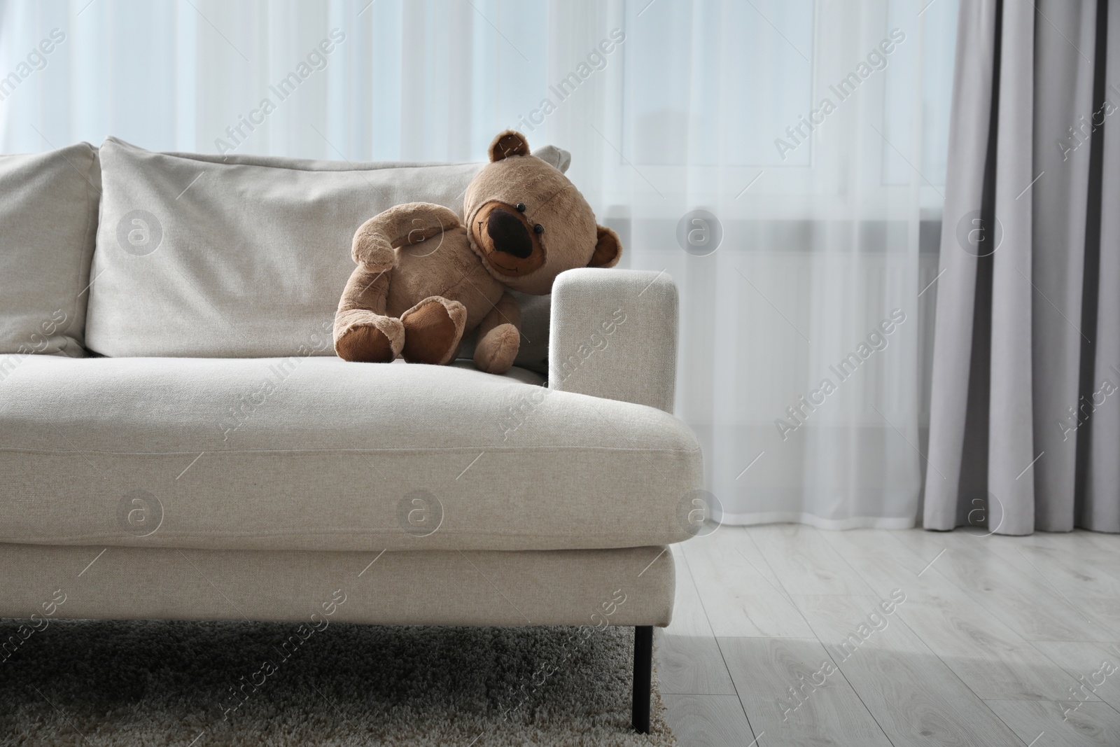 Photo of Cute lonely teddy bear on sofa in room. Space for text