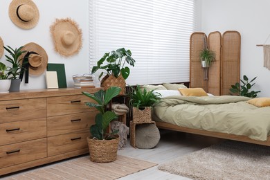 Photo of Comfortable bed and beautiful green houseplants in bedroom