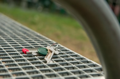 Photo of Keys forgotten on metal bench outdoors. Lost and found