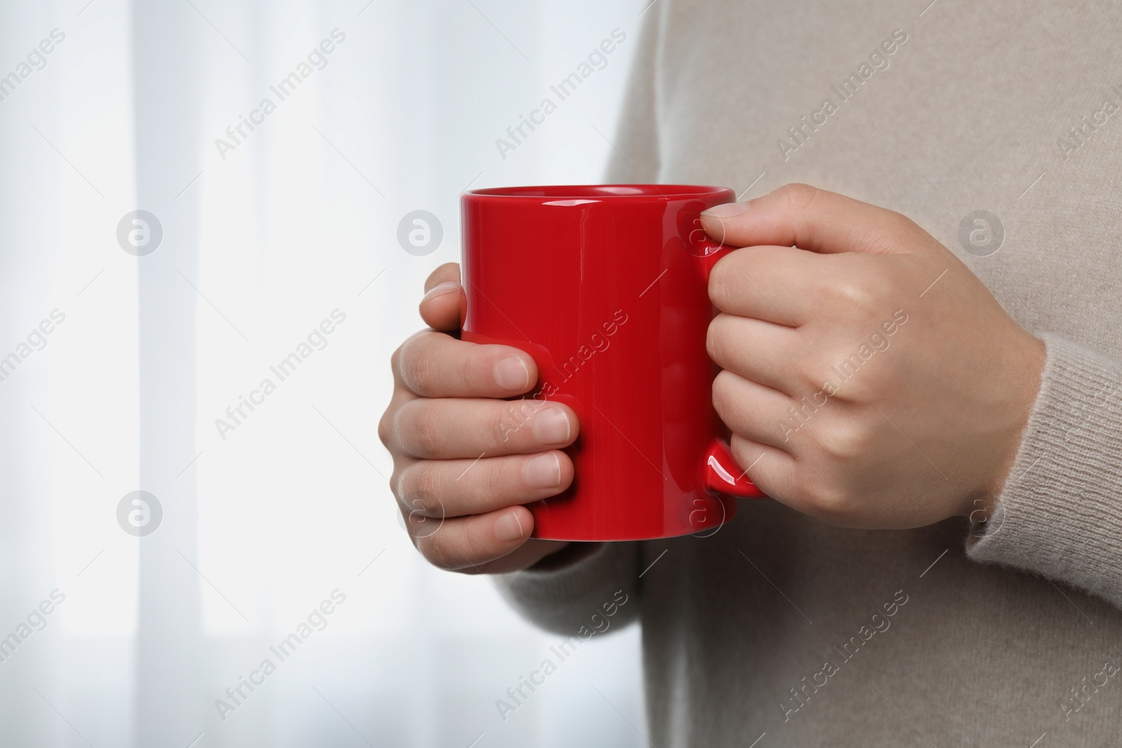 Photo of Woman holding red mug indoors, closeup view