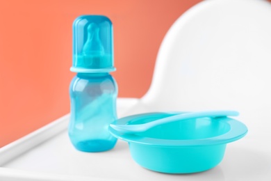 Photo of Set of plastic dishware on white feeding table. Serving baby food