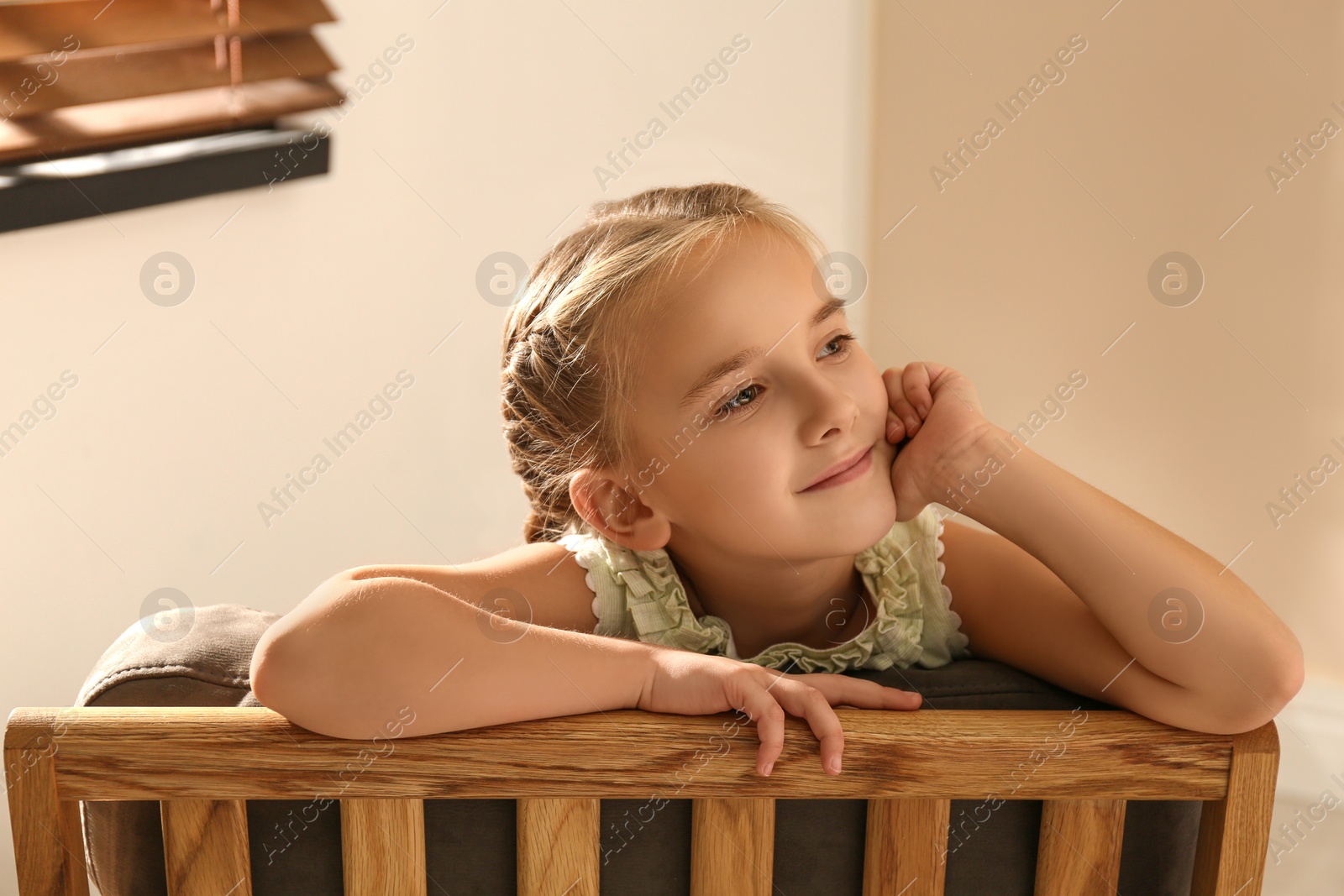 Photo of Little girl sitting in armchair at home