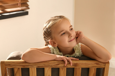 Little girl sitting in armchair at home