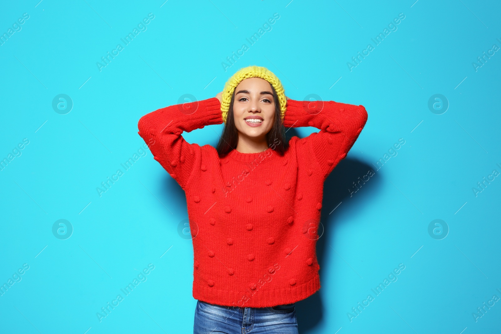 Photo of Young woman in warm sweater and hat on color background. Celebrating Christmas