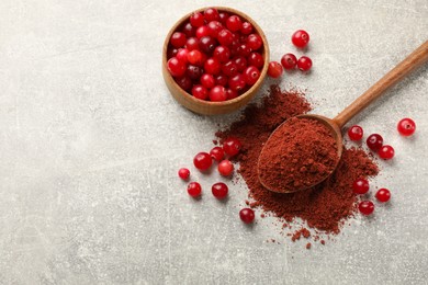 Photo of Cranberry powder and fresh berries on light grey table, top view. Space for text