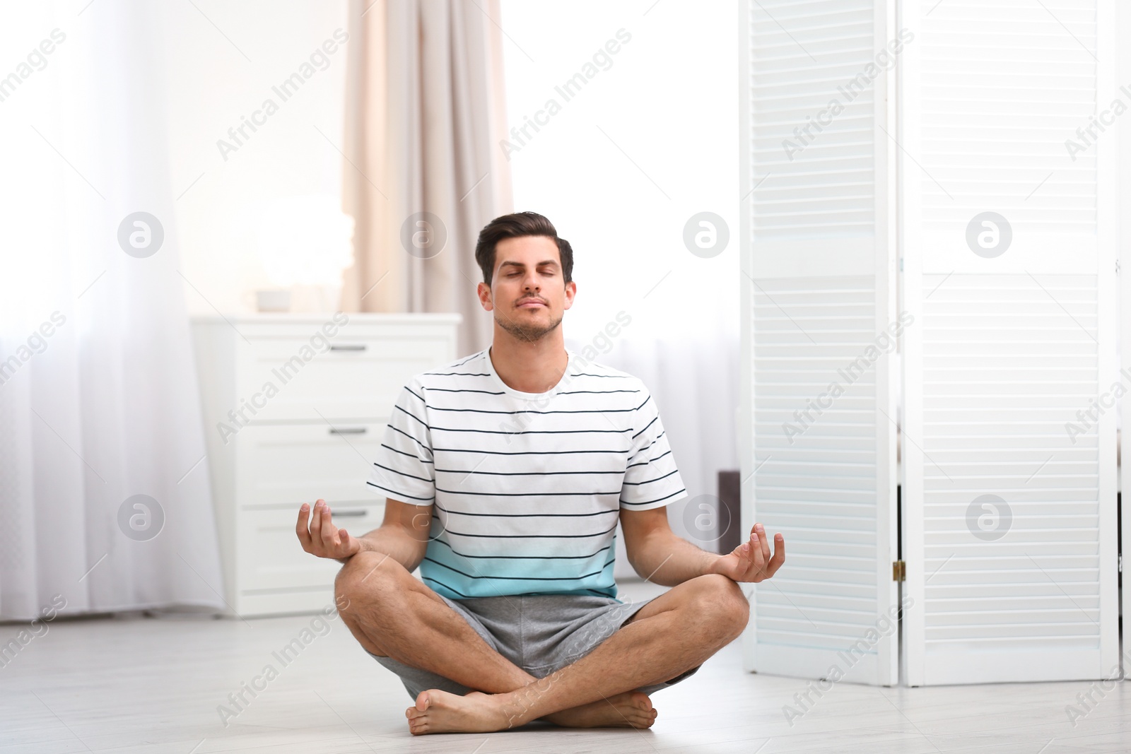 Photo of Man meditating on floor at home. Zen concept